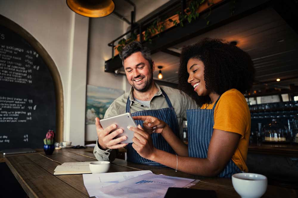 Image of two business partners smiling as they choose something together on an ipad.