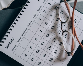 Image of a printed calendar on the month of January with a pair of glasses on top.