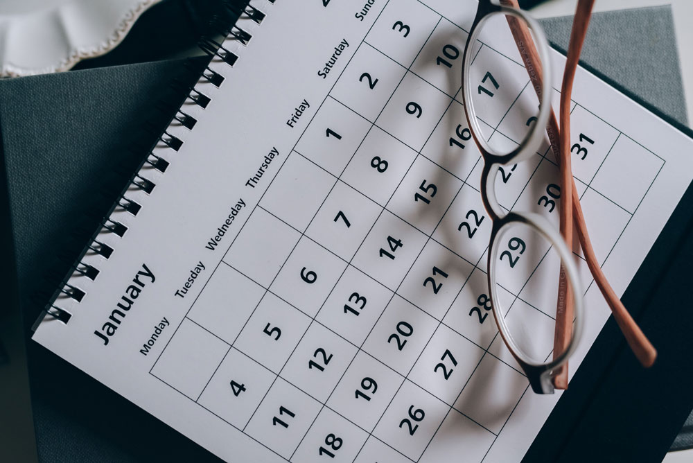 Image of a printed calendar on the month of January with a pair of glasses on top. 