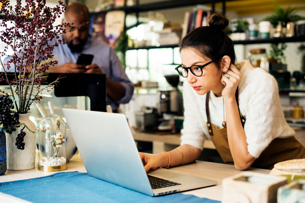 Image of small business woman looking at her computer as she works from her counter.