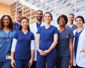 Image of a group of hospital healthcare workers grouped up, smiling at the viewer.