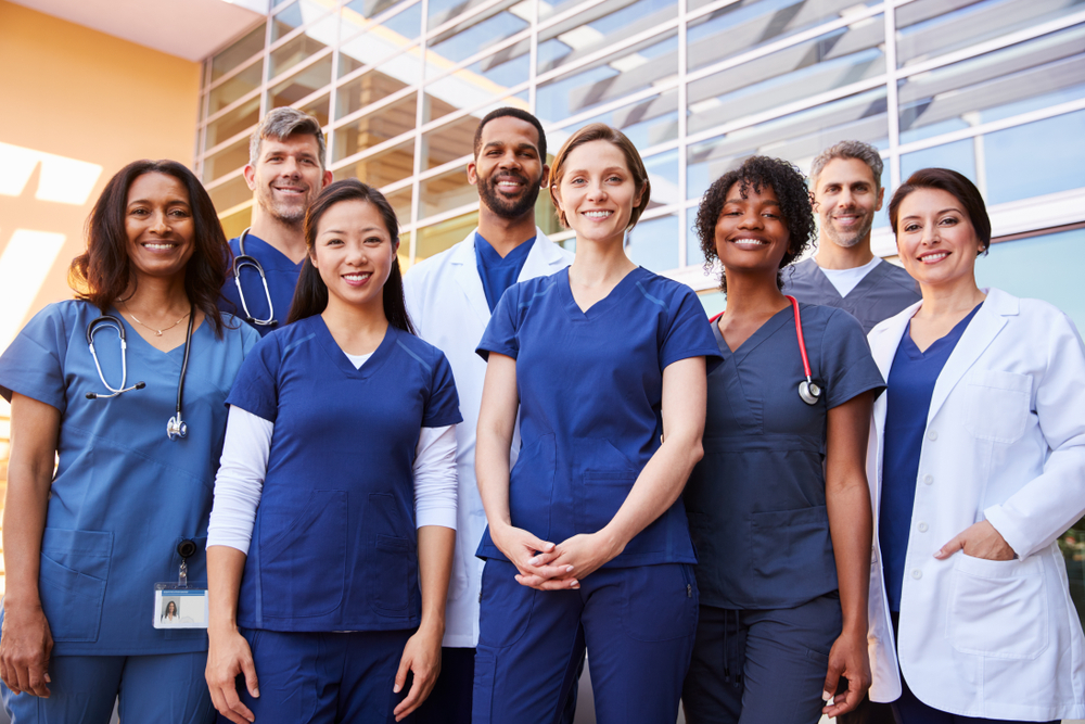 Image of a group of hospital healthcare workers grouped up, smiling at the viewer.