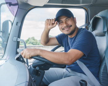 Image of truck driver smiling and tipping his hat.