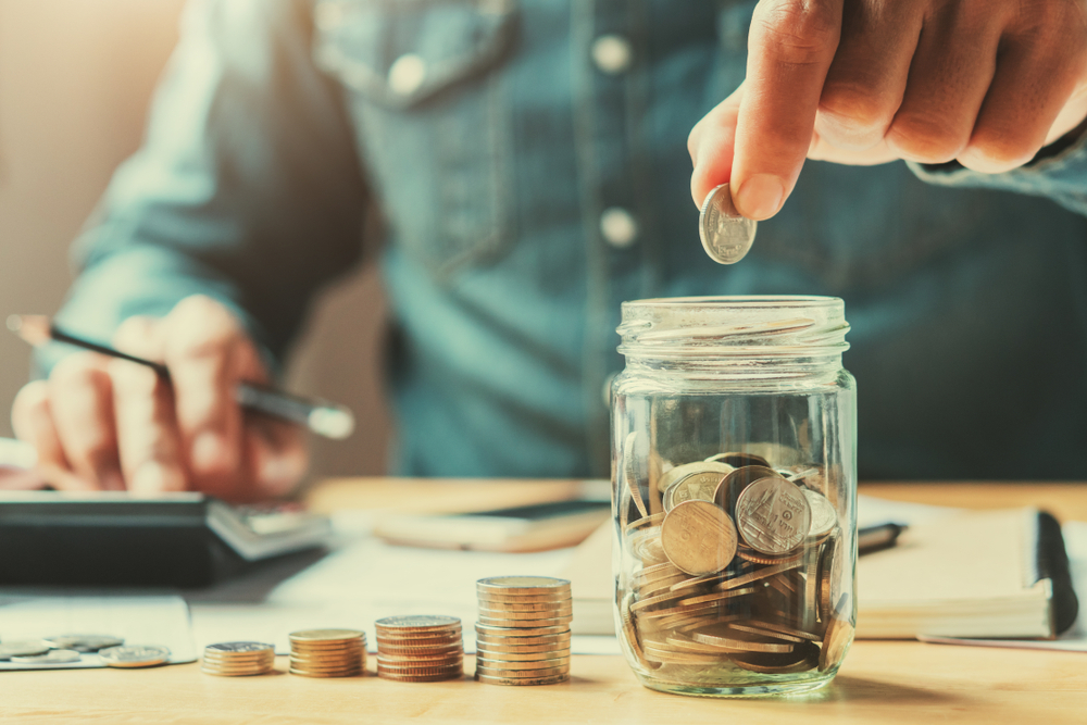 Image of someone separating change into stacks and into a jar. 