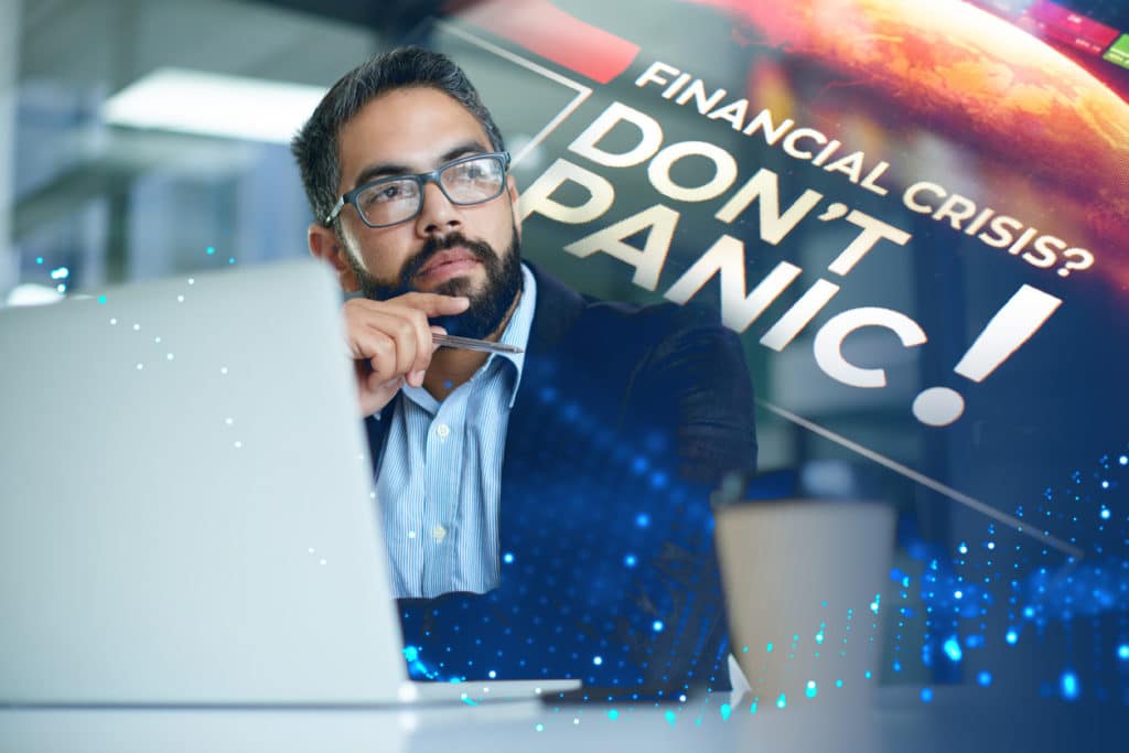 Image of man sitting at his desk with a laptop. He looks on at the horizon while an image saying "Financial crisis? Don't Panic!"