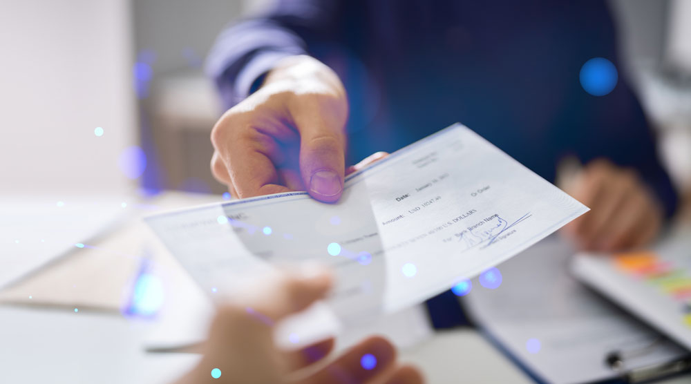 Image of someone handing someone else a check from across the table. The other person is reaching out to take the check from them.